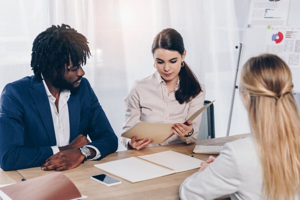 Selective focus of multicultural recruiters conducting job interview with employee at table in